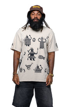 Man wearing a beige t-shirt with black screen printed African graphics and a brown Cooyah bucket hat on a white background.