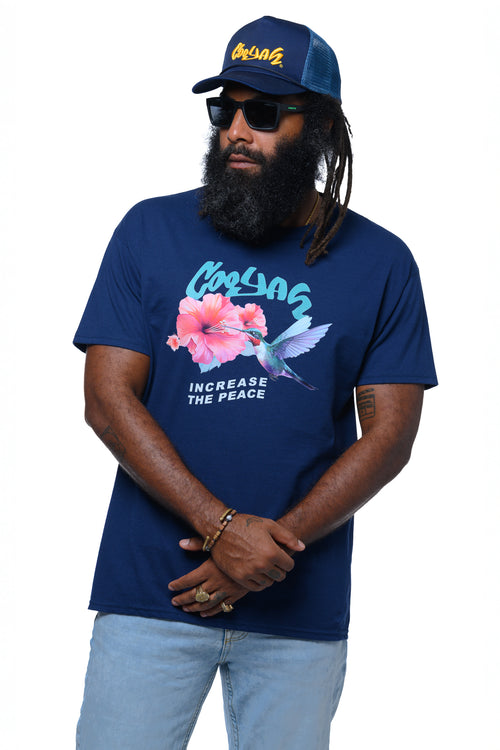 Man wearing a navy blue t-shirt with a colorful graphic and text, "increase the peace" with pink hibiscus flower and hummingbird design paired with a navy blue trucker cap and sunglasses on a white background.  Cooyah Clothing brand.
