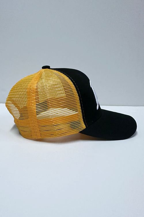Black and yellow mesh cap on a white surface with a light gray background