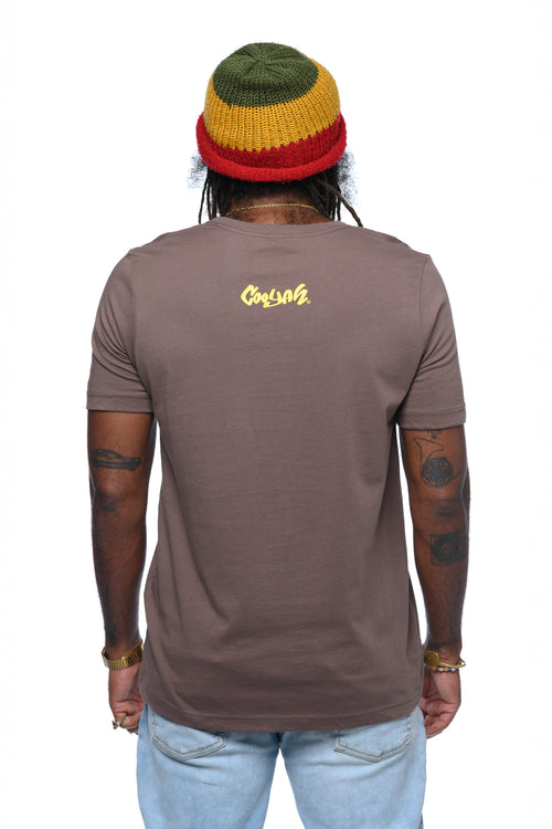 Man wearing a brown t-shirt with a Cooyah logo on the back, rasta knit beanie standing against a white background.
