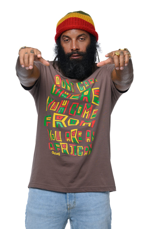 Man wearing a brown t-shirt with colorful text in rasta colors and a beanie on a white background.  Cooyah the official reggae clothing brand since 1987.