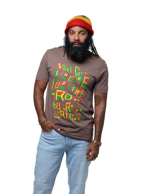 Man wearing a brown t-shirt with colorful text, blue jeans, and a colorful beanie on a white background