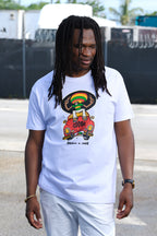 Reggae Singer Kumar Fya in a Cooyah graphic t-shirt featuring a rasta cartoon character on a red VW Beetle Car with the text 'COOYAH' and 'PEACE = LOVE' below it, paired with white pants in an outdoor setting.