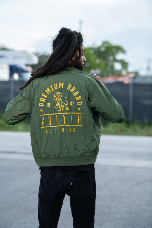 Cooyah Clothing. Men's Premium Brand Bomber Jacket with gold Lion print on olive green fabric. We are a Jamaican streetwear clothing brand established in 1987.