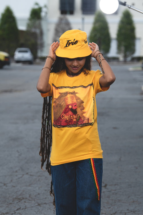 Cooyah Clothing - Women's Haile Selassie Rastafari Lion graphic tee in gold. Crew neck, short sleeve, soft, ringspun cotton. As a Jamaican owned clothing brand since 1987, we take pride in bringing you this classic rasta shirt.