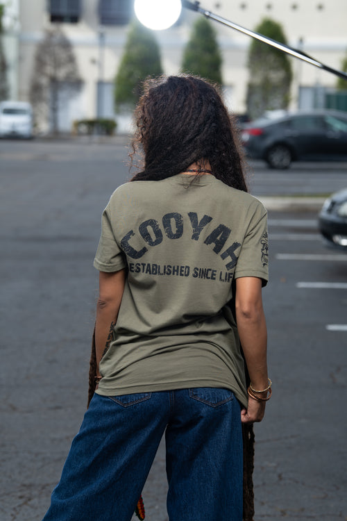 Cooyah Clothing - Women's Olive green graphic tee. As a Jamaican owned clothing brand since 1987, we take pride in bringing you this classic shirt. Don't wait, get yours now!