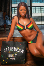 Woman in a colorful bikini sitting next to a 'Caribbean Built' tote bag complete with screen printed Cooyah logo. 