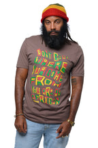 Man wearing a brown reggae t-shirt with colorful text 'Don't Care Where You Come From You Are An African' and a rasta beanie on a white background.  Cooyah Clothing brand.