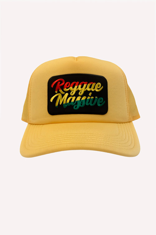 A yellow trucker hat with a black rectangular patch on the front that reads 'Reggae Massive' in red, yellow, and green lettering, set against a light gray background.  Jamaican clothing brand, Cooyah.
