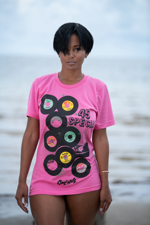 Cooyah Jamaica. Women's short sleeve graphic tee with 45 RPM Vinyl records screen printed on the front. Vintage reggae and rocksteady style. Pink boyfriend-fit Shirt, short sleeve, ringspun cotton. Jamaican streetwear clothing brand. IRIE