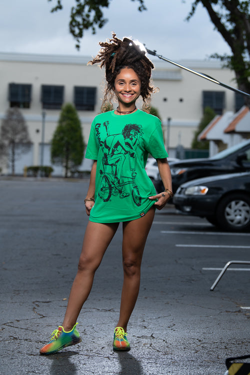 Cooyah Jamaica. Women's relaxed fit Simmer Down T-Shirt featuring a Rastaman on a bicycle design. Ring Spun Cotton, Short Sleeve  green Tee. Jamaican streetwear clothing brand.