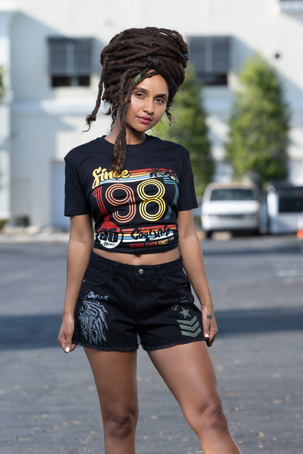 Cooyah Jamaican clothing brand.  Retro style women's black graphic tee with colorful 1987 design on the front.